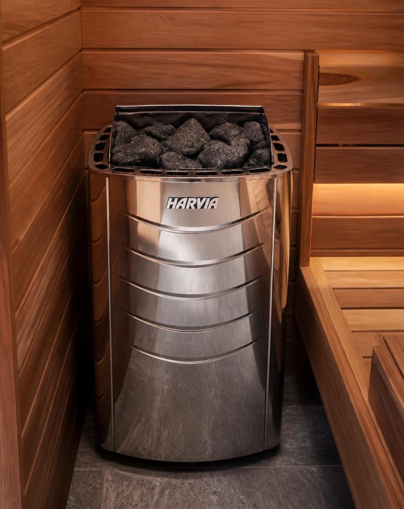 Stainless steel Harvia electric sauna heater with dark sauna stones inside a cedar-lined sauna